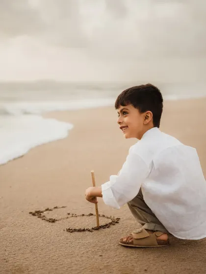 A young boy draws the number five in the sand to celebrate his birthday. This is a creative and personal shot from his outdoor milestone photoshoot.