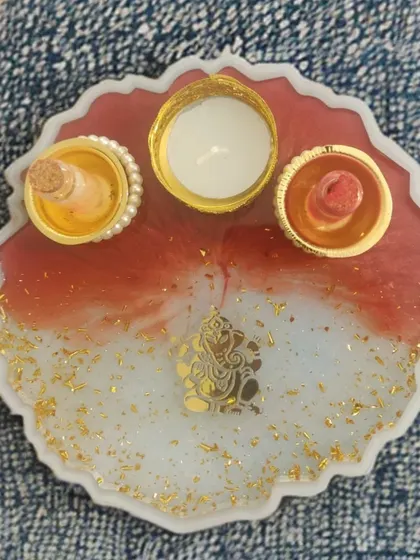 This is another one of my custom pooja thalis, designed to be a gorgeous addition to your festive decor. It features a Ganesha motif on a red and white resin base with sparkling gold flakes and dedicated holders for your pooja essentials.