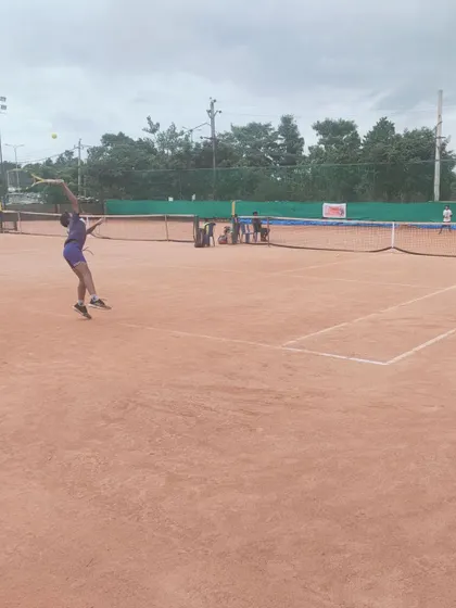 A young female player executes a jump serve with precision during the AITA TS7 U-14 main draw matches.