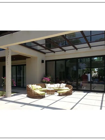 A beautifully contrived home in Khandala. This image shows the outdoor lounge area, where comfortable wicker furniture sits under a pergola, blending the interiors with the natural surroundings.