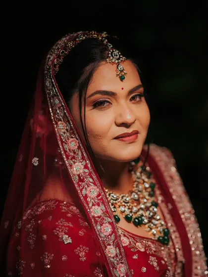 A dramatic and captivating bridal portrait. For this Varamala look, I created a defined, smokey eye and a bold lip to match the richness of the bride's red and emerald ensemble, ensuring she looked like a queen.