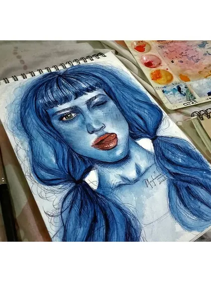An angled shot of my winking blue portrait, showing the texture of the paper and the ink lines that define the features.