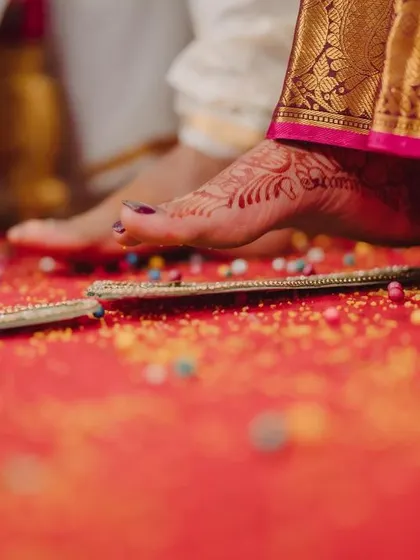 A symbolic shot of the bride's foot during the Saptapadi ritual, representing the seven steps and vows of marriage.