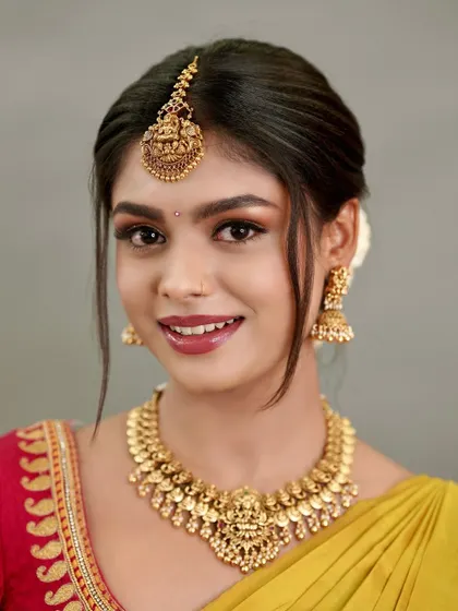 A beautiful portrait of a bride wearing a classic Kaasu necklace. I styled this simple yet elegant look with a Lakshmi maang tikka and matching jhumkas, perfect for a pre-wedding ceremony.