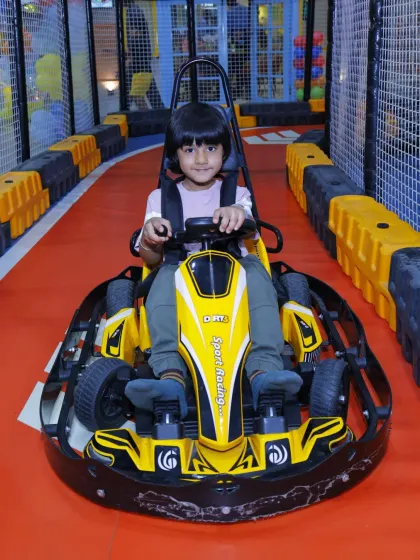 A young boy takes his position at the starting line, ready for an exciting race in his yellow go-kart.