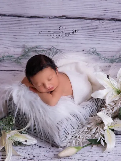 Simple and elegant. A baby boy sleeping on a bed of white fur, framed by beautiful white lilies. This shows that floral themes can be perfect for boys too.