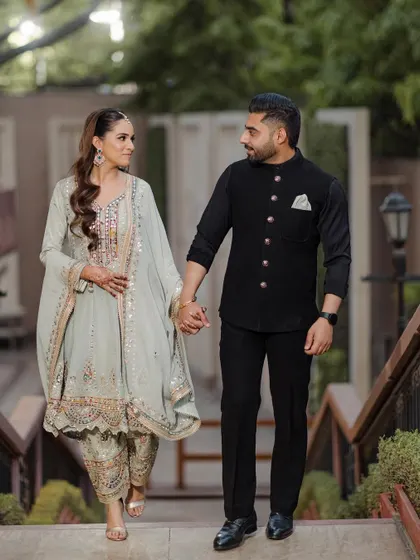 A beautiful shot of a couple walking hand-in-hand, dressed in elegant traditional attire for their Roka ceremony. This is a perfect example of a classic, graceful engagement portrait.