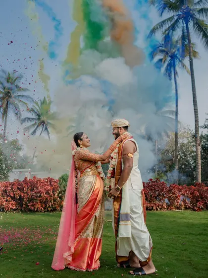 A colorful varmaala exchange against a backdrop of palm trees and smoke bombs. We love incorporating creative elements to make your wedding photos unique and spectacular.