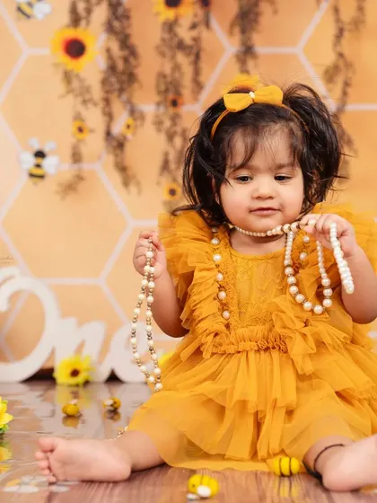 A thoughtful moment captured during our honeybee-themed shoot, showing her playing with a string of pearls.