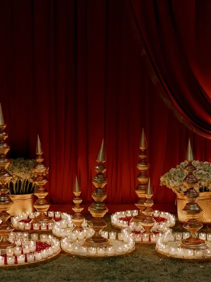 Traditional brass spires are surrounded by rings of candles and flower petals. This type of floor decor helps to define spaces and adds a warm, ambient glow throughout the venue.