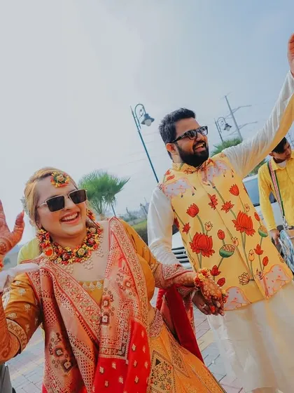 The bride and groom making their entrance with dhol players. Their happy waves and sunglasses add a cool, fun vibe to this candid shot.
