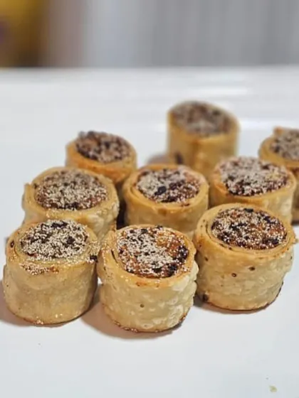 These are baked savory rolls, a modern take on a traditional snack. They are filled with a spiced mixture and offer a delightful crunch, perfect as a pass-around appetizer.