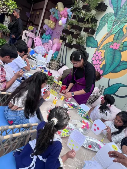 A wide view of our outdoor party setup. You can see kids fully engaged in painting their planters, with a beautiful balloon arrangement and themed decor creating a festive atmosphere.