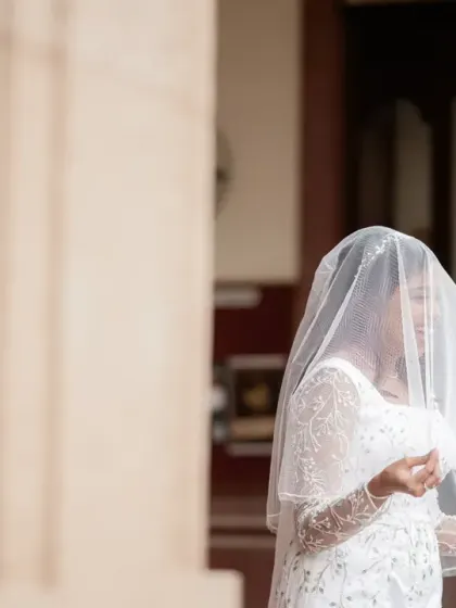 An artistic shot of the bride, her face partially obscured by her delicate veil. This portrait is both mysterious and beautiful, highlighting the elegance of her bridal look.