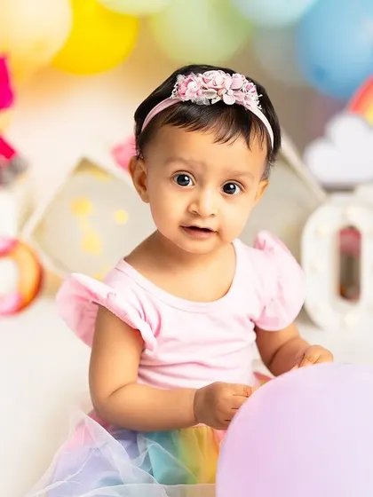 A sweet portrait from a rainbow and unicorn themed first birthday. Her curious expression before the cake smash begins is a precious moment to remember.