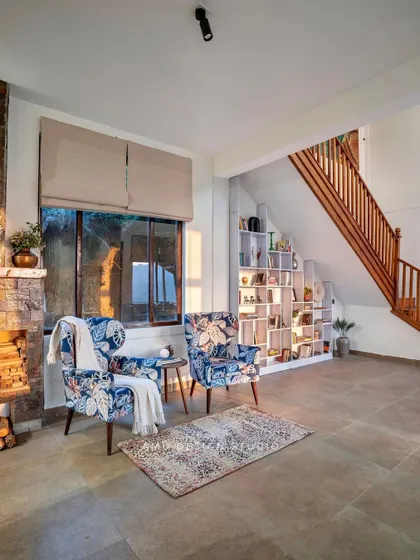 A cozy corner by the fireplace in 'The Mountain Home.' We added two custom-upholstered armchairs with a floral pattern to create an intimate seating area for warmth and conversation.