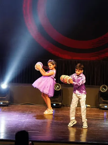 A side view of the kids' drum dance, showing their focus and coordination as they perform with their props.