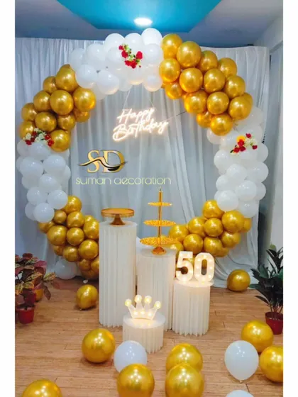 A classic 50th birthday decoration with a white and gold balloon ring, plinths, and a '50' marquee number.