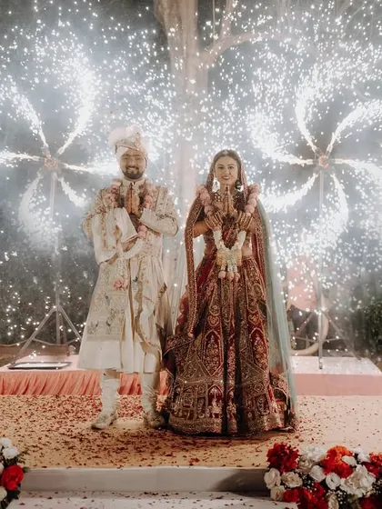 A grand Varmala ceremony moment, with the couple framed by spectacular fireworks, creating a truly magical and celebratory atmosphere.