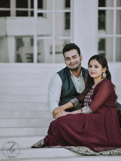 A simple and sweet pre-wedding portrait of a couple holding hands while sitting on white steps. Their comfortable and relaxed posture shows their easy connection.