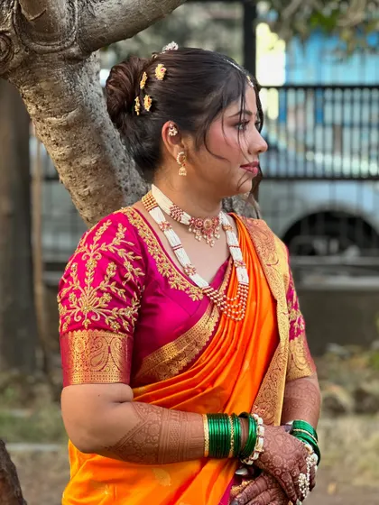 A side view highlighting the neat bridal bun and the intricate details of the pearl jewellery.