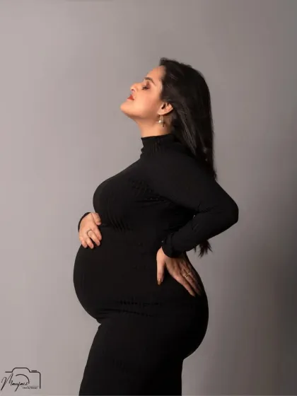A powerful and confident solo portrait, showcasing the beautiful silhouette of the baby bump in a sleek black bodycon dress.