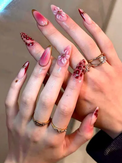 A bold and dramatic bridal look with sharp stiletto nails, featuring a deep red ombré, 3D florals, and intricate beadwork. This set is for the bride who wants to make a statement.