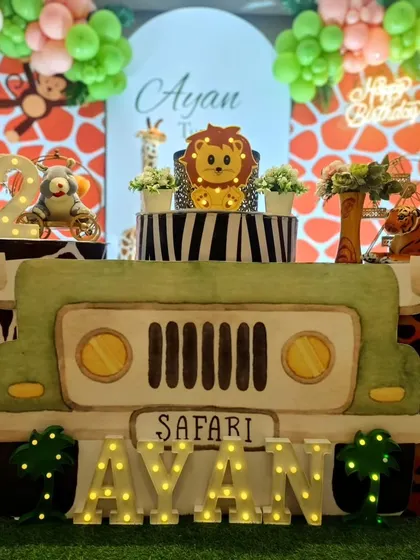 A custom safari jeep table is the centerpiece of this setup for Ayan's second birthday. The light-up name in front adds a personalized touch that shines.