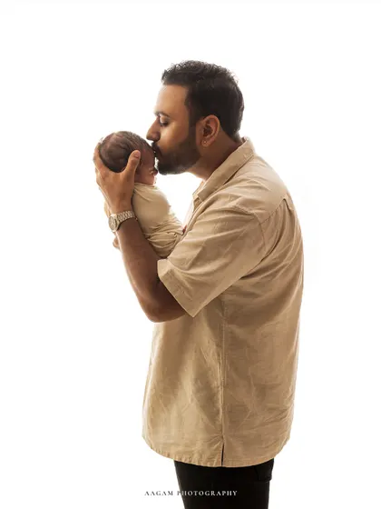 A father's gentle kiss for his newborn. This simple, high-key portrait is filled with tenderness and love, capturing a quiet moment of connection.