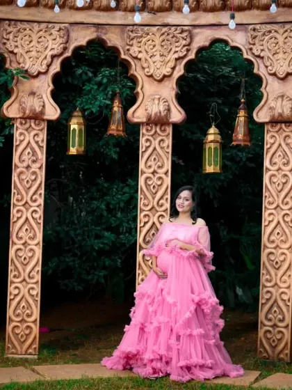 This pink ruffle maternity gown looks stunning against an ornate backdrop. Its design provides a flattering fit while adding a touch of glamour to the photoshoot.