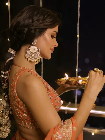 Lighting the diyas with a festive glow. This side profile shows the intricate braid and the beautiful earrings that complete the Diwali look.