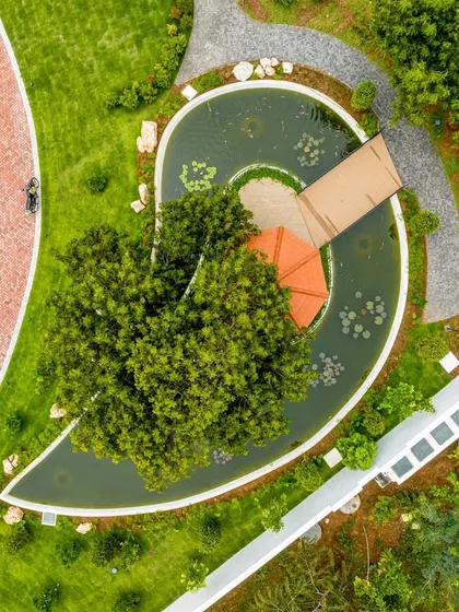 A detailed aerial view of the heart-shaped pond with a gazebo at its center. This water body acts as a natural cooling element and a picturesque focal point within the landscape design.