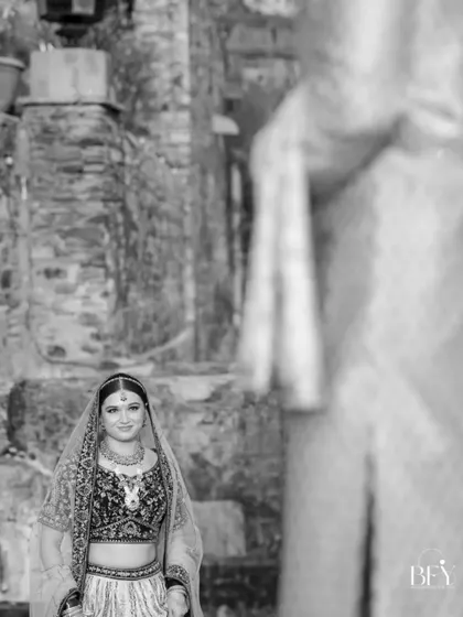 A black and white shot of the bride looking towards the groom, who is out of focus in the foreground, creating a sense of anticipation.