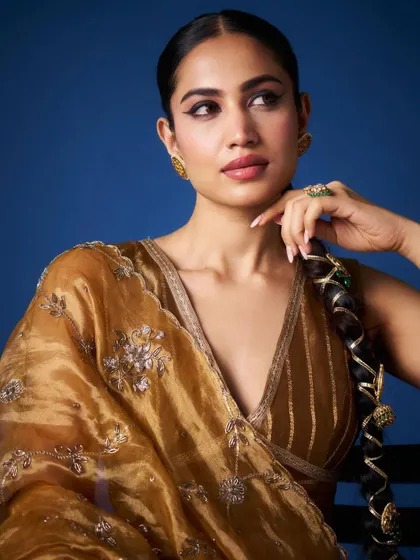 The warm glow of a golden organza saree. The delicate silver embroidery adds a touch of sparkle, while the plunging neckline of the blouse gives it a modern feel. I styled this look with a braided hairstyle for a touch of traditional charm.