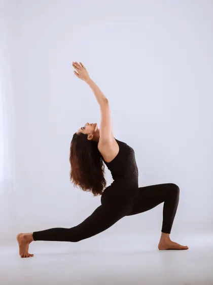 A clean, minimalist shot of a yoga pose against a white background. The focus is on the form, alignment, and grace of the body.