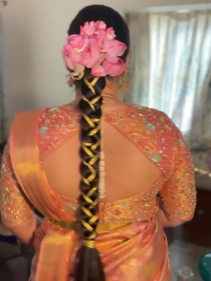 The back view of the braid with lotus petals and a yellow ribbon woven through. This shows how we can incorporate different elements to match your outfit.