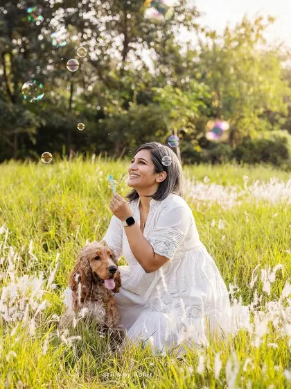 Bubbles, sunshine, and a happy Cocker Spaniel. This photo is pure happiness, capturing a whimsical moment between a woman and her dog in a sun-drenched field.