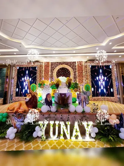 A wide shot of the grand jungle party, showing the impressive stage, marquee letters, and the overall lavish setup in a large banquet hall.