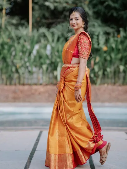 A full-length view of bridal grace. The makeup, hair, and saree come together to create a look of timeless elegance, perfect for her walk down the aisle.