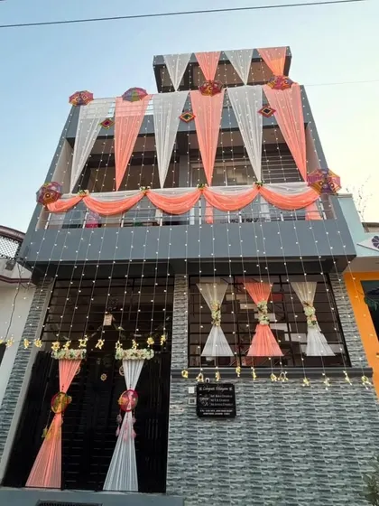A modern house decorated with peach and white drapes and fairy lights. This design complements the architecture of the house while adding a festive wedding touch.