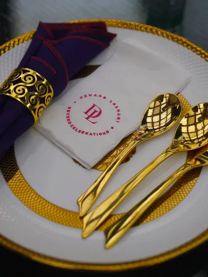 Every detail is considered in our table settings. This place setting features our custom-branded napkin, elegant gold-rimmed plate, and ornate cutlery, reflecting our commitment to luxury.