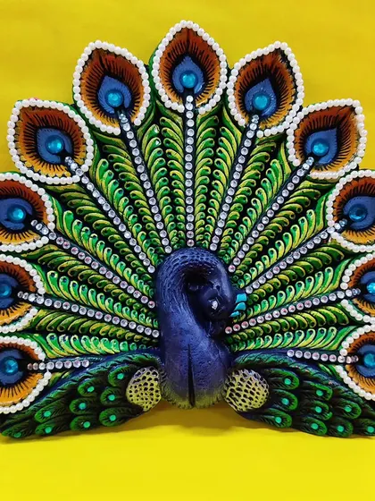 An ornate peacock-shaped diya, beautifully decorated for festive occasions. Our craft workshops often include seasonal items like diya and rakhi making.