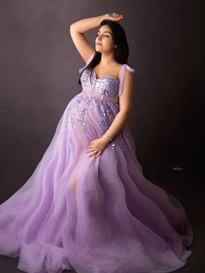 A powerful and graceful pose. The mom-to-be looks absolutely divine in this lavender gown, with one hand gently resting on her bump and the other raised.