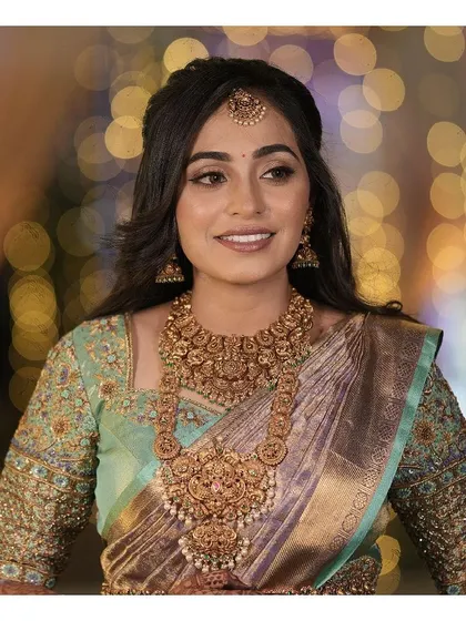 A beautiful portrait of a bride on her wedding day. Her soft glam makeup, with a focus on luminous skin and gentle eye definition, perfectly complements her traditional gold jewellery and silk saree.