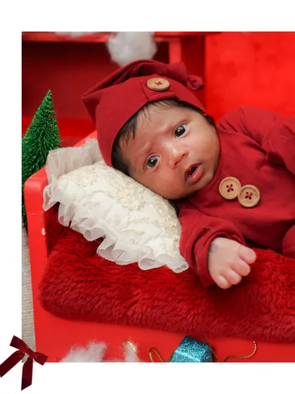 A close-up of the baby in his little red outfit and hat. This is a perfect shot for a personalized Christmas card.