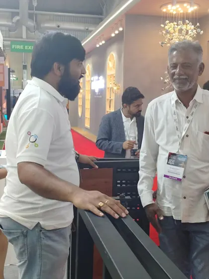 Another angle of me interacting with a visitor at our exhibition stand. I am always happy to answer questions and provide detailed information about my products.