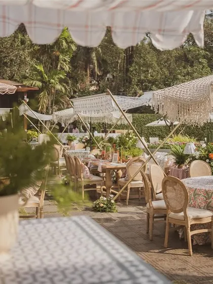 A wide view of the brunch setup, showing the mix of dining tables and lounge areas under macrame-fringed umbrellas.