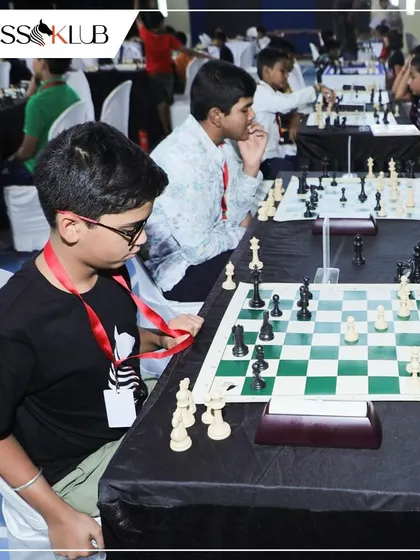 Young competitors, wearing their participant lanyards, concentrate on their boards during a large tournament, showcasing the serious and professional atmosphere.