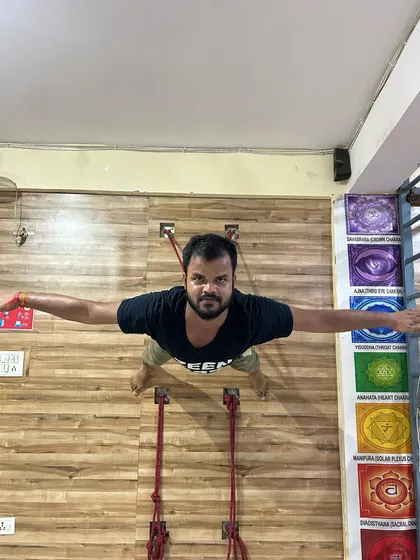 Seen from above, this student demonstrates the strength and control required to hold his body parallel to the floor using only the wall ropes. This is a testament to dedicated practice.