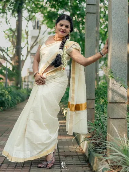 A full-length shot of the Kerala saree, styled with a traditional long braid adorned with jasmine flowers. This look is perfect for Onam or any cultural celebration.